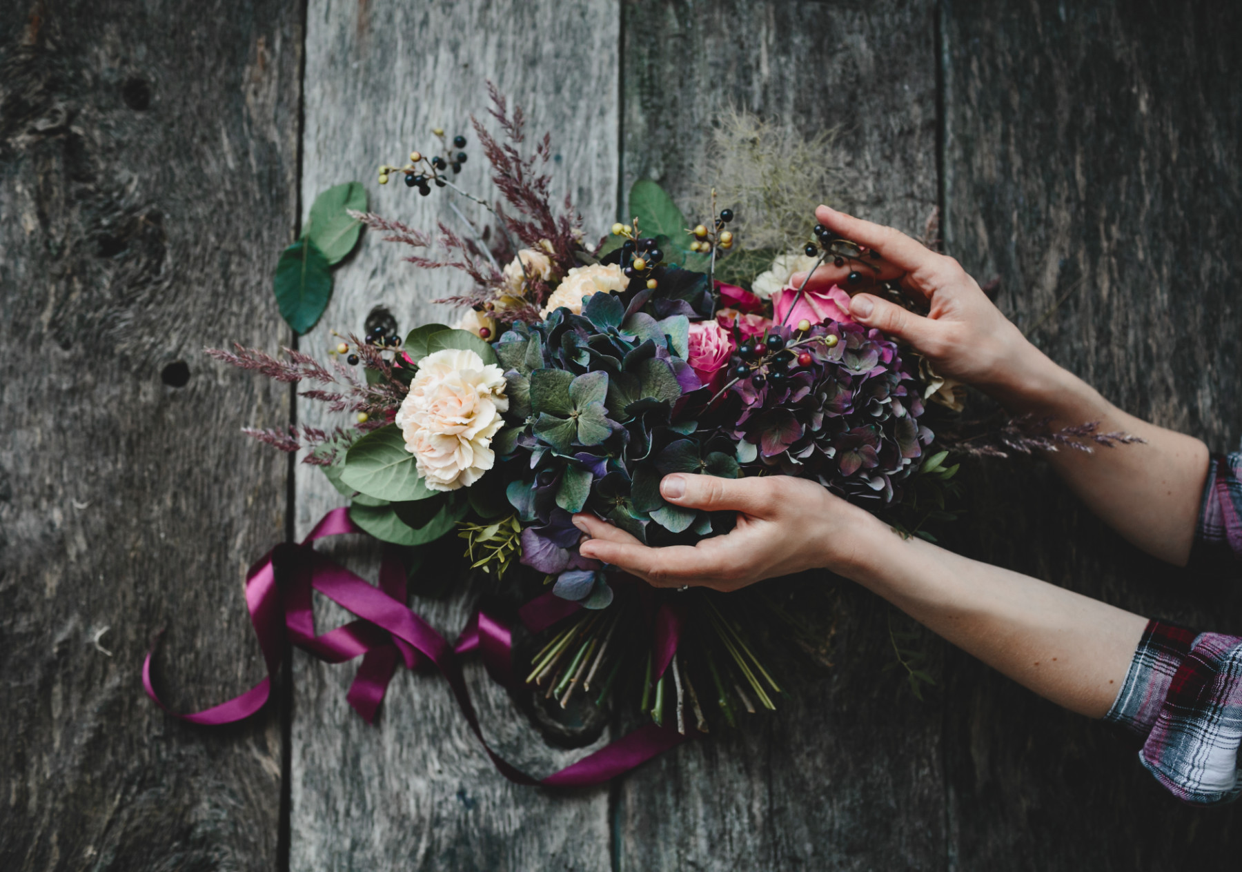 rich bouquet of dark flowers and white roses lies on wooden tabl